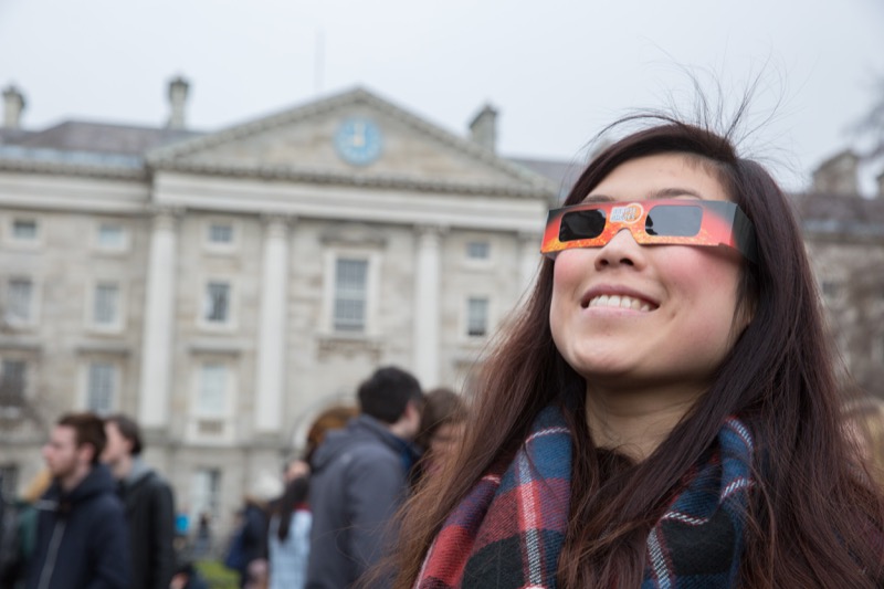 A spectator sporting safety glasses waits for a glimpse of the solar eclipse.